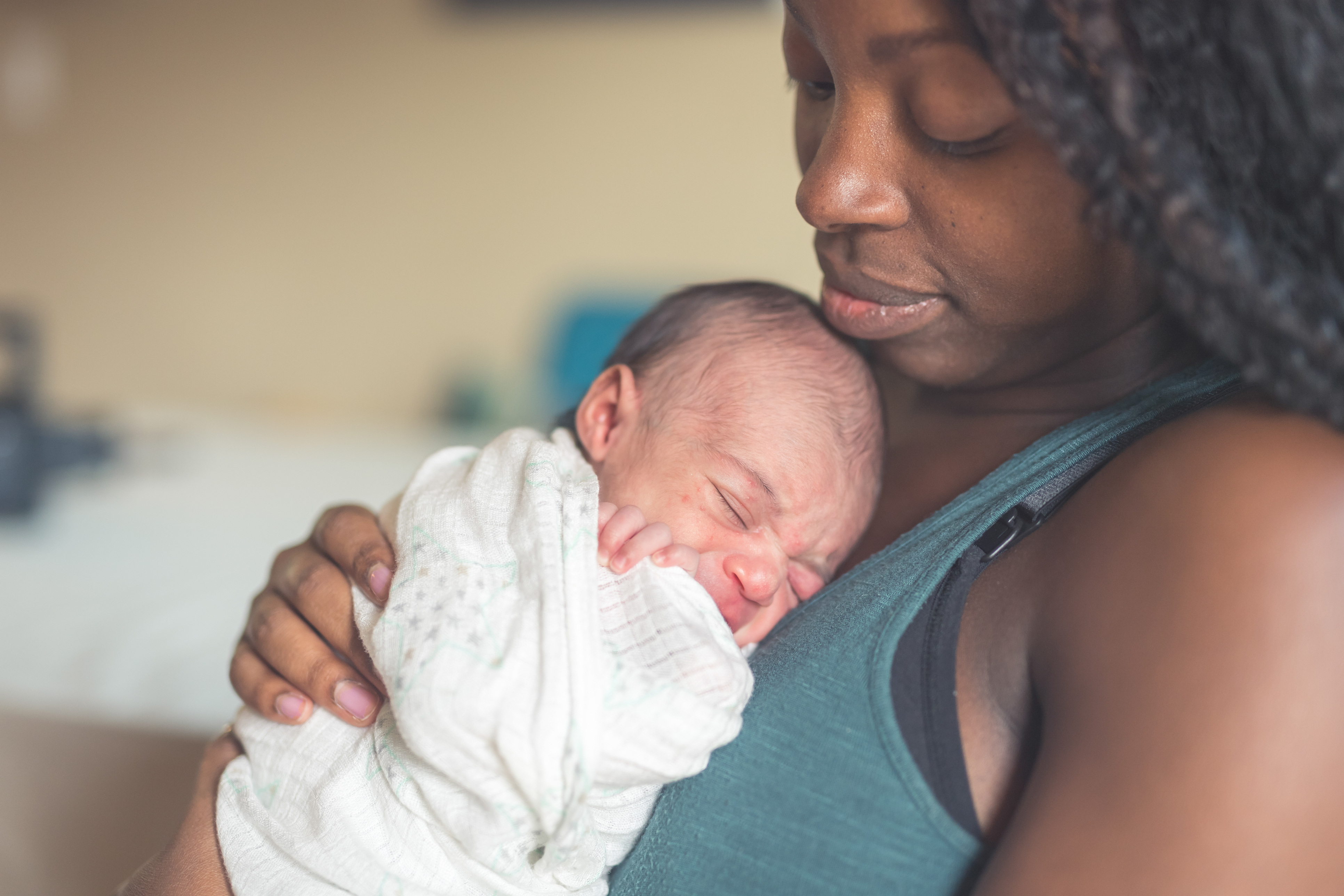 Black mother holds her newborn baby against her chest